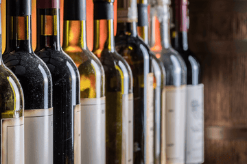 A row of wine bottles with blank labels lined up closely together