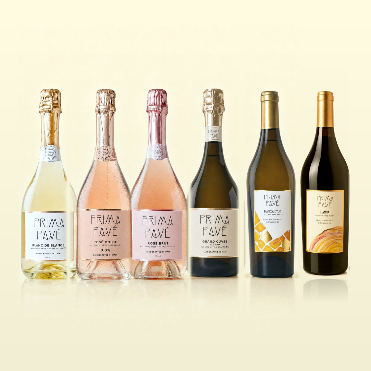 Prima Pavé Complete Collection — all six 0.0% Italian wines side by side: Blanc de Blancs, Rosé Dolce, Rosé Brut, Grand Cuvée 2nd Edition, Bianca D'Or and Fiamma. The labels read ALCOHOL FREE and HANDCRAFTED IN ITALY; the Fiamma label reads PRODOTTO IN ITALIA and 0.0% ALCOHOL.